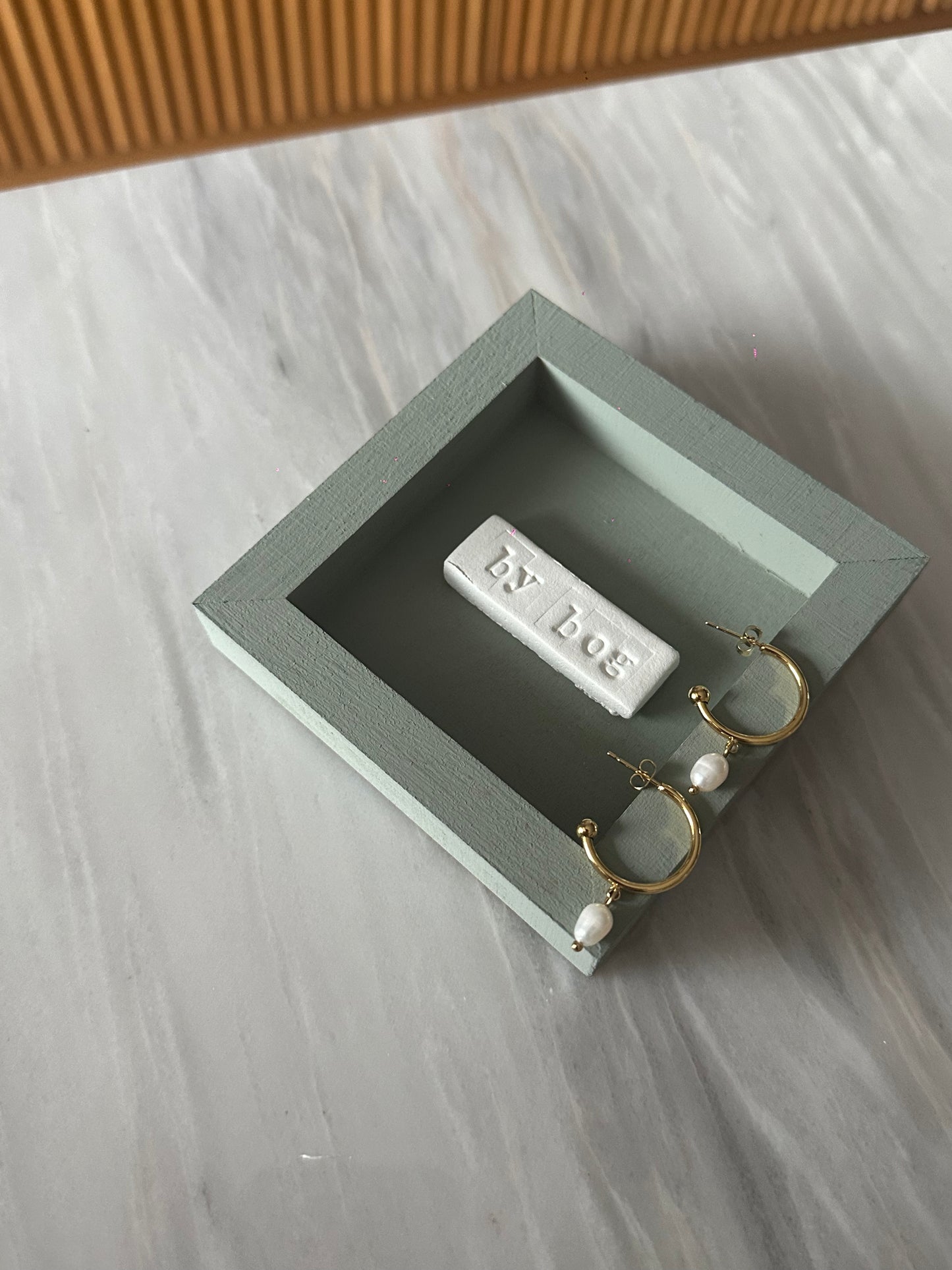 Pendientes de aro de acero inoxidable en color dorado con perla de río colgando. Estos pendientes son perfectos para elevar tus looks.