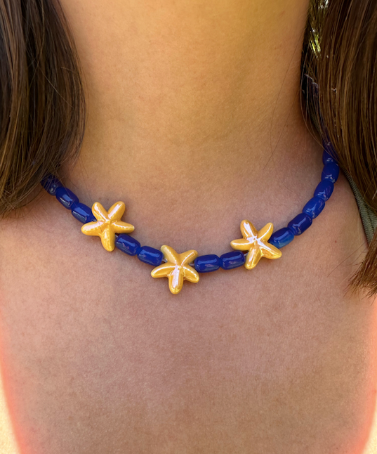 Collar hecho a mano con cuentas de cerámica en azul y tres estrellas de cerámica en amarillo en el centro. Con cierre ajustable en acero inoxidable