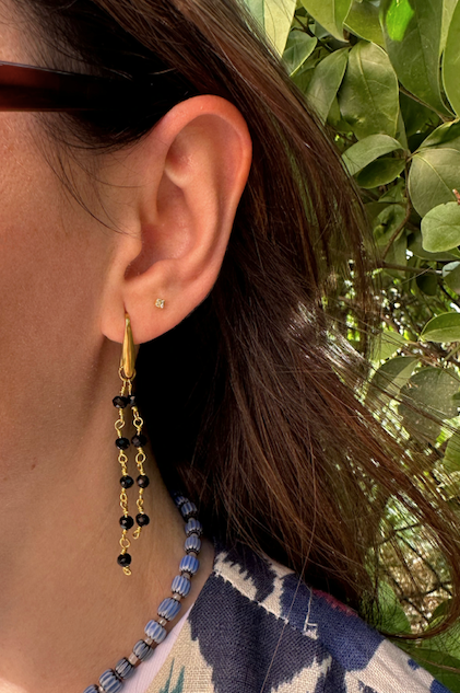 Pendientes hechos a mano de acero inoxidable con cadenas doradas con bolitas de color negro en diferentes alturas.