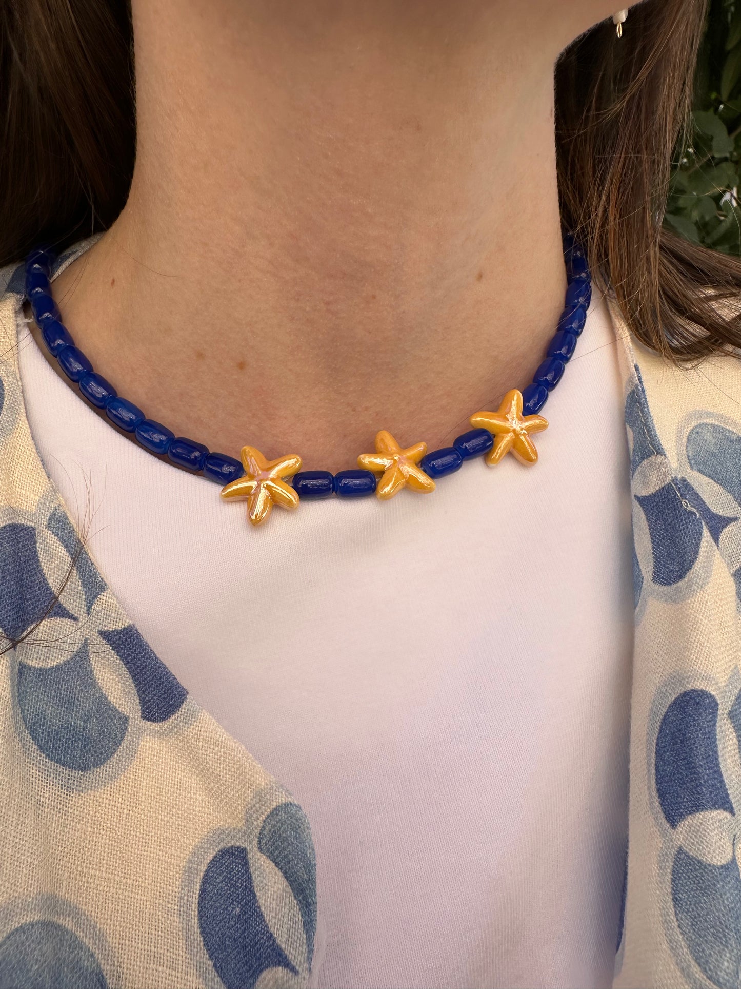 Collar hecho a mano con cuentas de cerámica en azul y tres estrellas de cerámica en amarillo en el centro. Con cierre ajustable en acero inoxidable