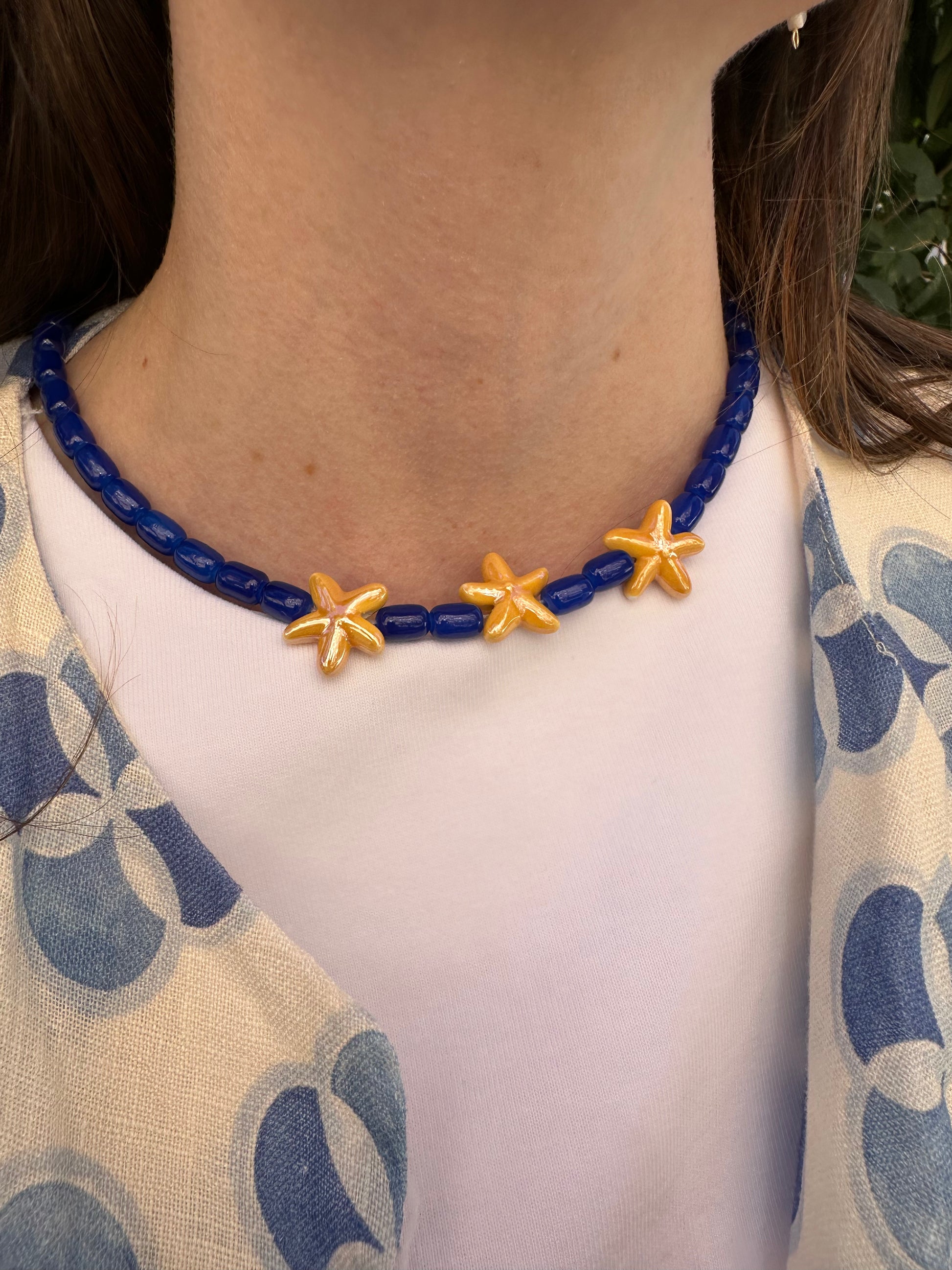 Collar hecho a mano con cuentas de cerámica en azul y tres estrellas de cerámica en amarillo en el centro. Con cierre ajustable en acero inoxidable