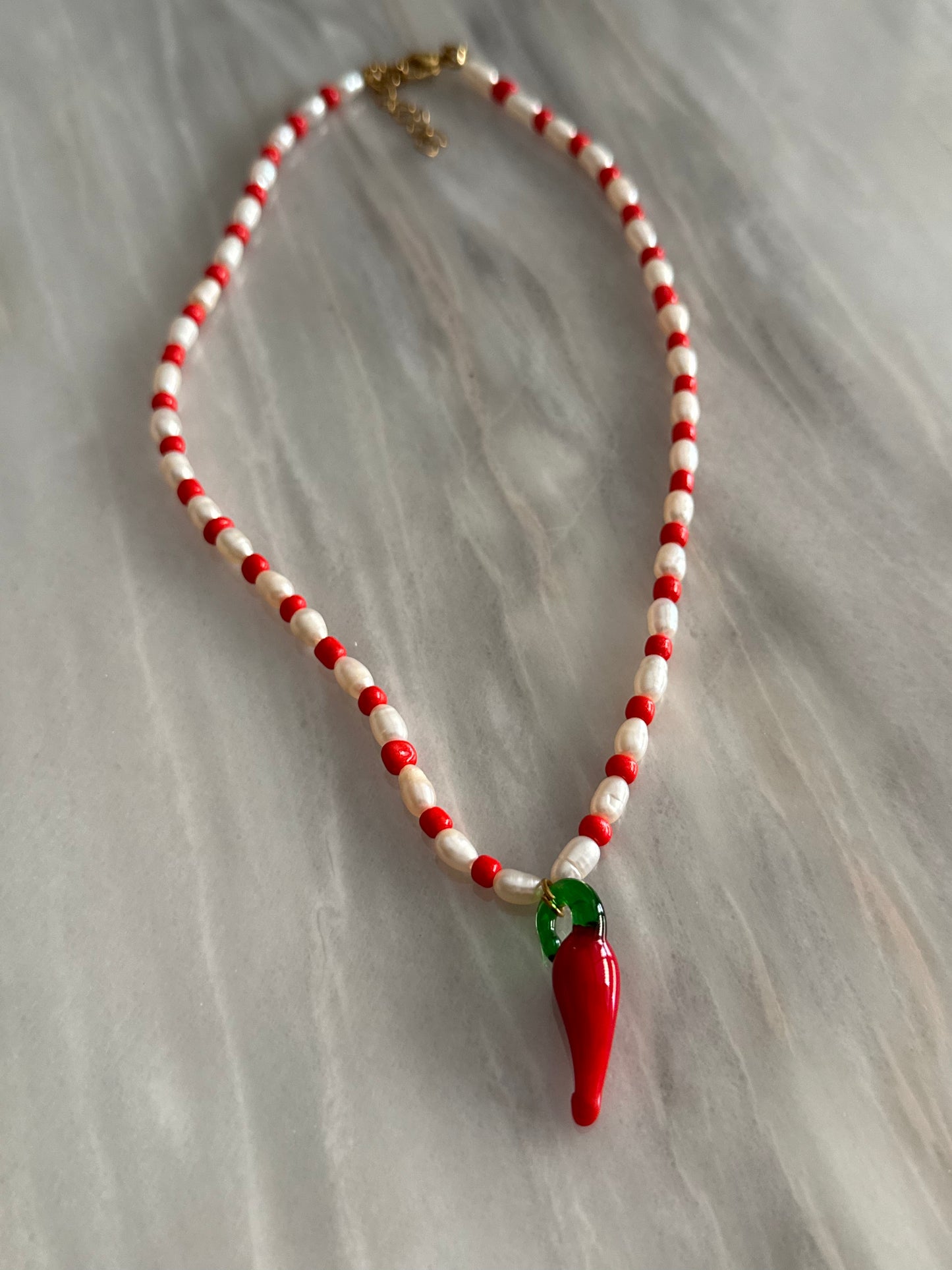 Collar hecho a mano con piedras de río y bolitas rojas, con un abalorio con forma de chili de cristal de murano en color rojo y verde