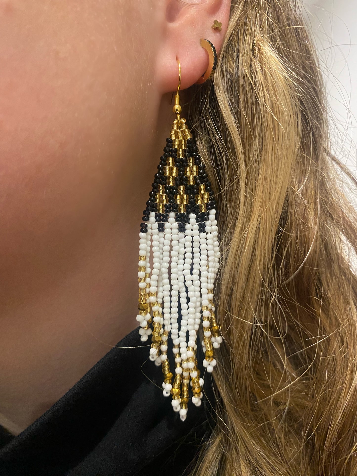 Pendientes de bolitas en tonos blancos, dorados y negros, hechos con técnica miyuki con una caída preciosa. Cierre de acero inoxidable.