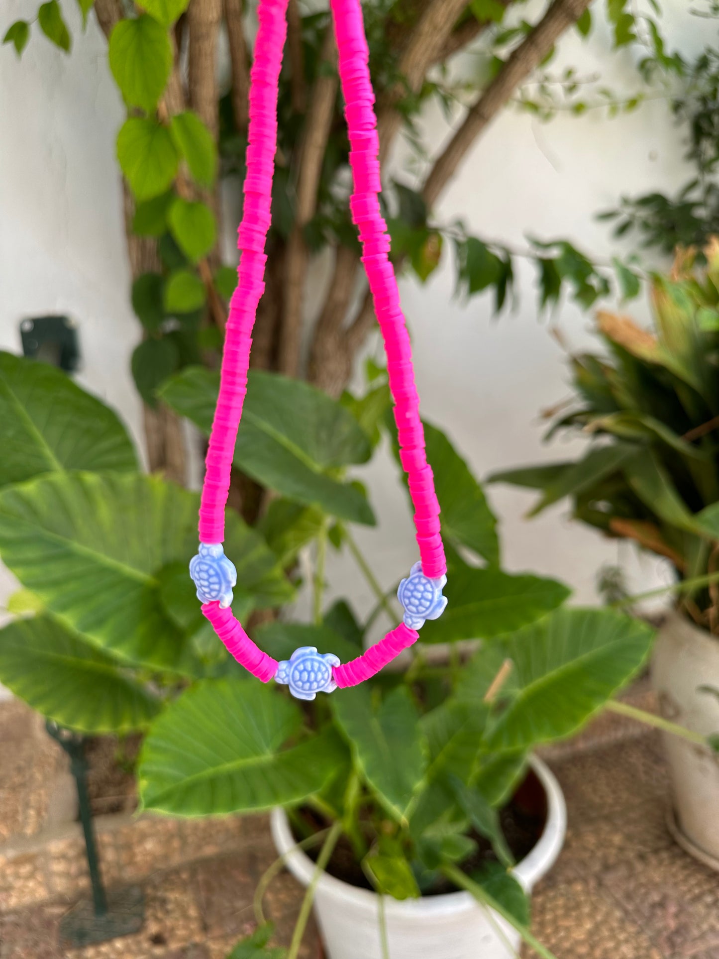 Collar hecho a mano con arcilla polimérica rosa fosforito y tres tortugas de cerámica en azul en el centro. Con cierre ajustable en acero inoxidable