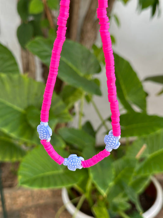 Collar hecho a mano con arcilla polimérica rosa fosforito y tres tortugas de cerámica en azul en el centro. Con cierre ajustable en acero inoxidable