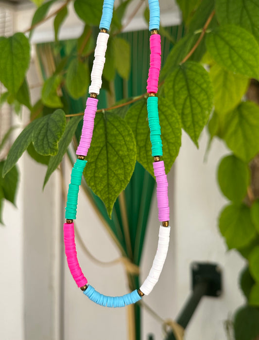Collar hecho a mano con arcilla polimérica en varios colores fosforitos: rosa, azul, verde, lila y blanco, separados por cuentas espaciadoras doradas. Con cierre ajustable en acero inoxidable