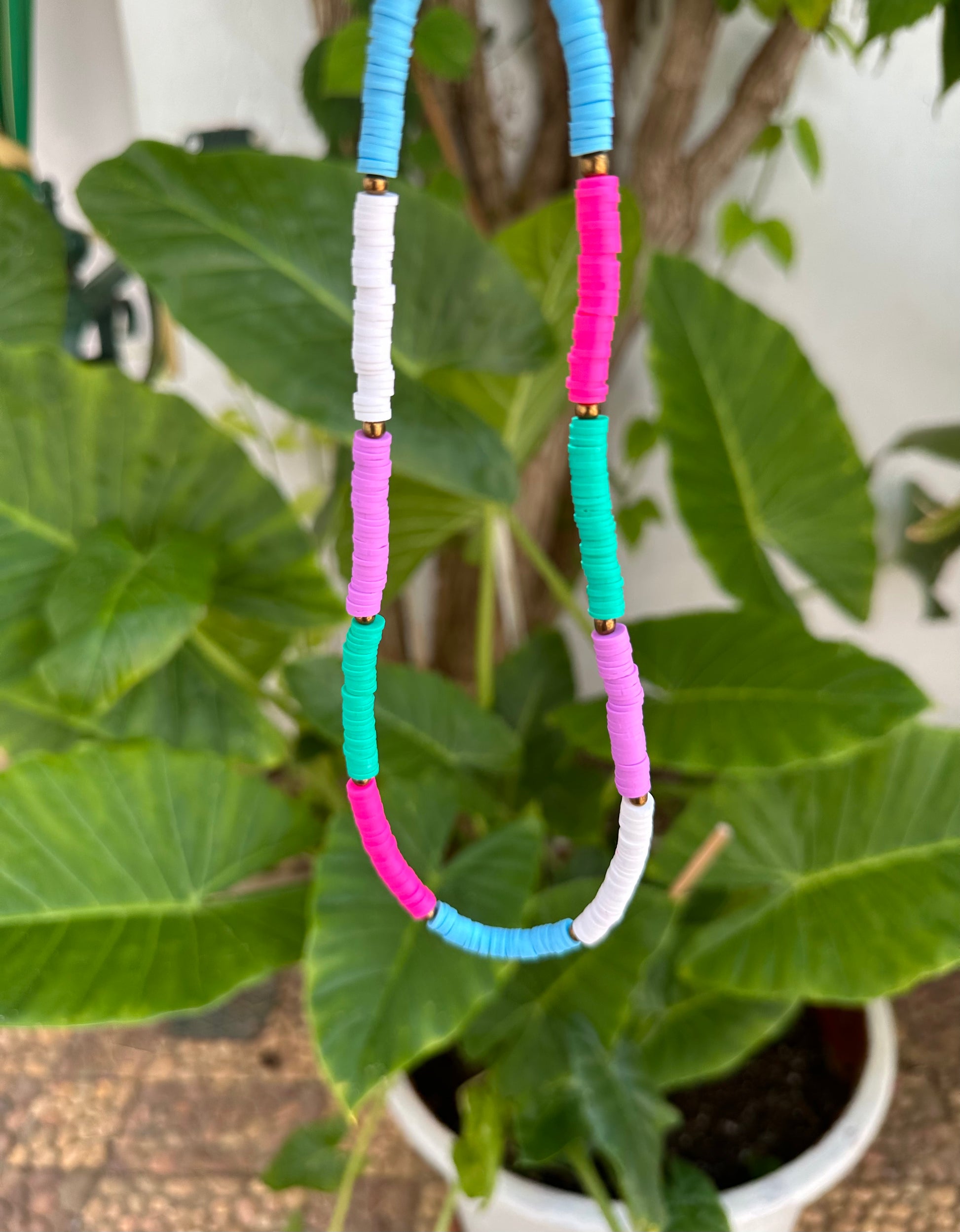 Collar hecho a mano con arcilla polimérica en varios colores fosforitos: rosa, azul, verde, lila y blanco, separados por cuentas espaciadoras doradas. Con cierre ajustable en acero inoxidable