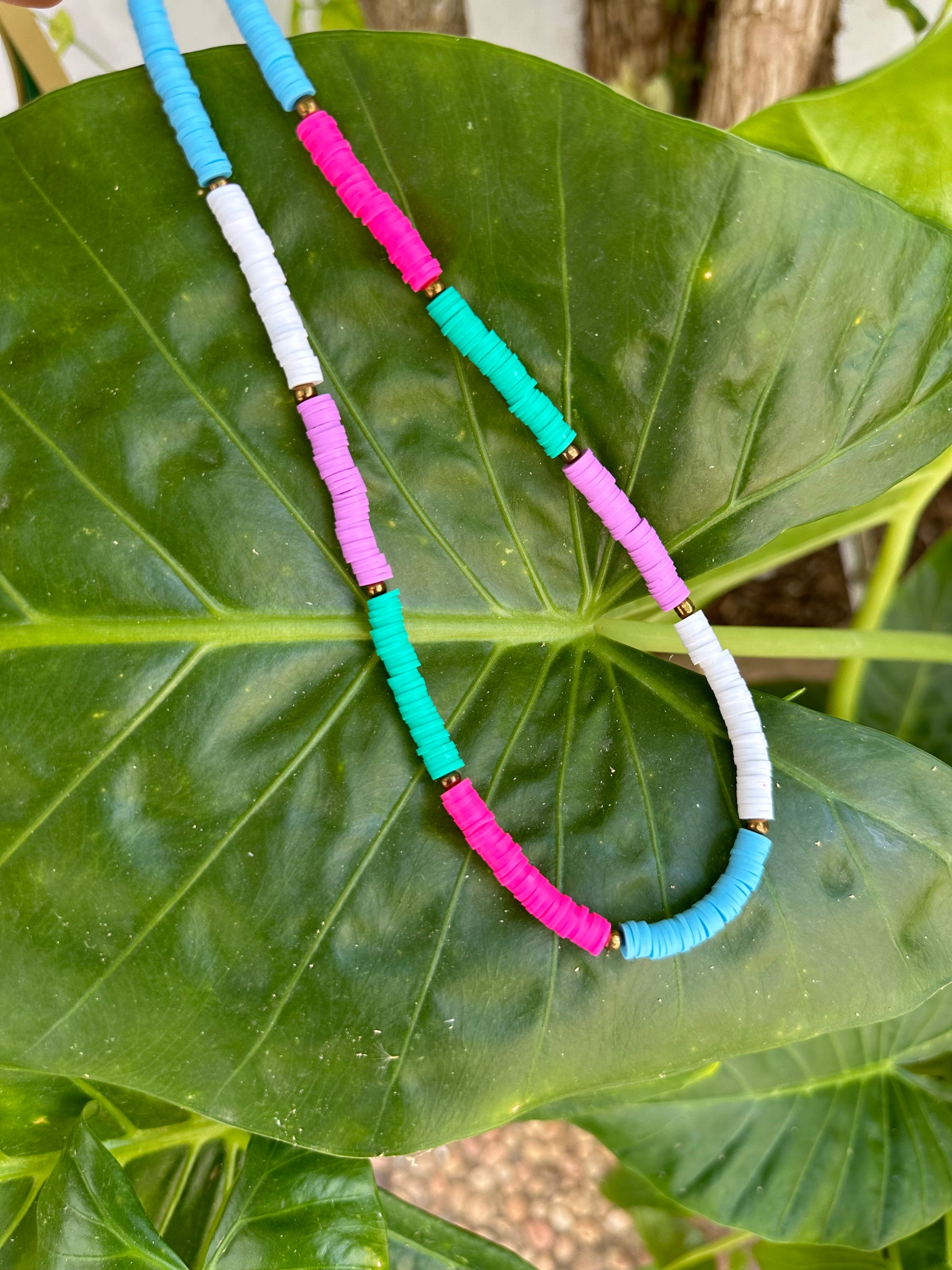 Collar hecho a mano con arcilla polimérica en varios colores fosforitos: rosa, azul, verde, lila y blanco, separados por cuentas espaciadoras doradas. Con cierre ajustable en acero inoxidable