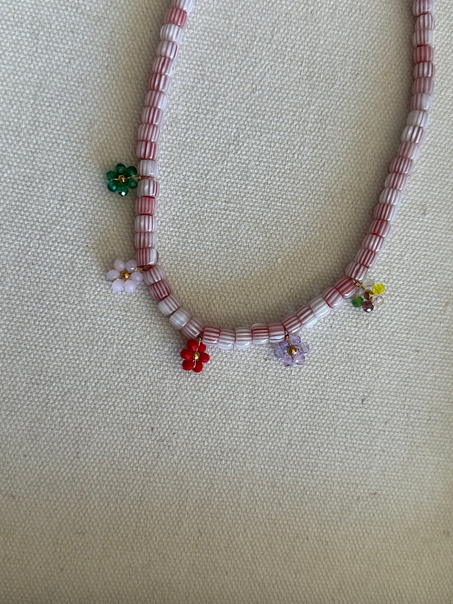 Collar hecho a mano con cuentas de cerámica blancas y bolitas formando florecitas. Cierre ajustable