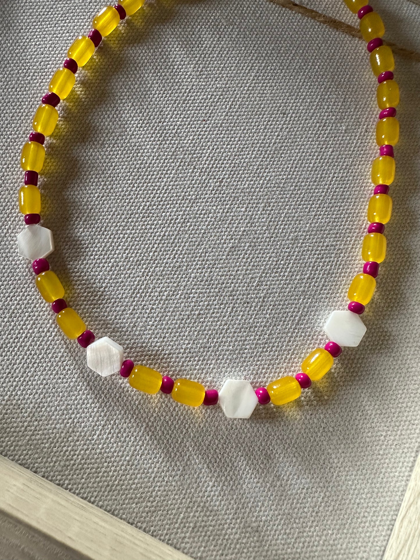 Collar hecho a mano con cuentas de cerámica amarillas, cuentas azules y con 4 hexágonos de nácar. Cierre ajustable de acero inoxidable