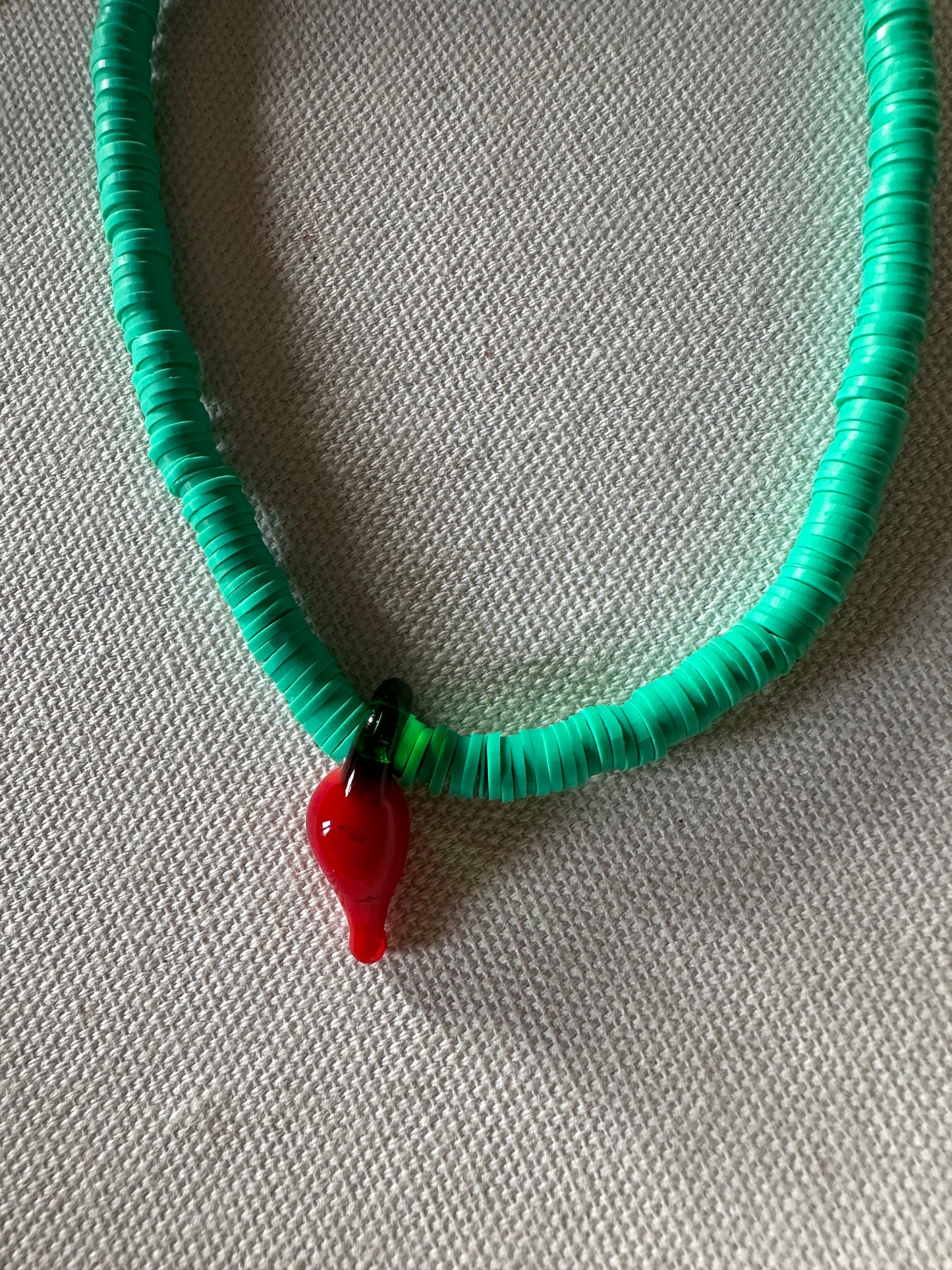 Collar hecho a mano con arcilla polimérica verde y con un abalorio con forma de chili de cristal de murano en color rojo y verde. Cierre ajustable de acero inoxidable,