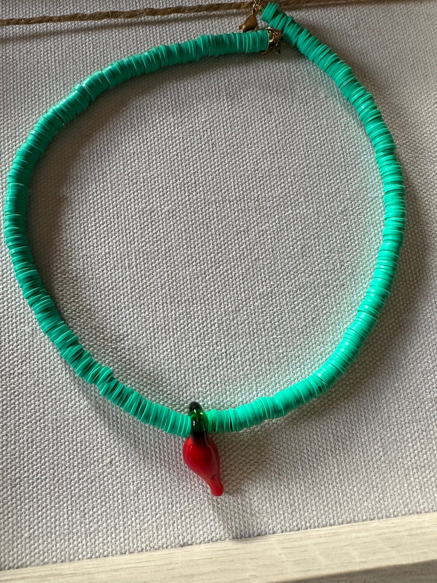 Collar hecho a mano con arcilla polimérica verde y con un abalorio con forma de chili de cristal de murano en color rojo y verde. Cierre ajustable de acero inoidable,