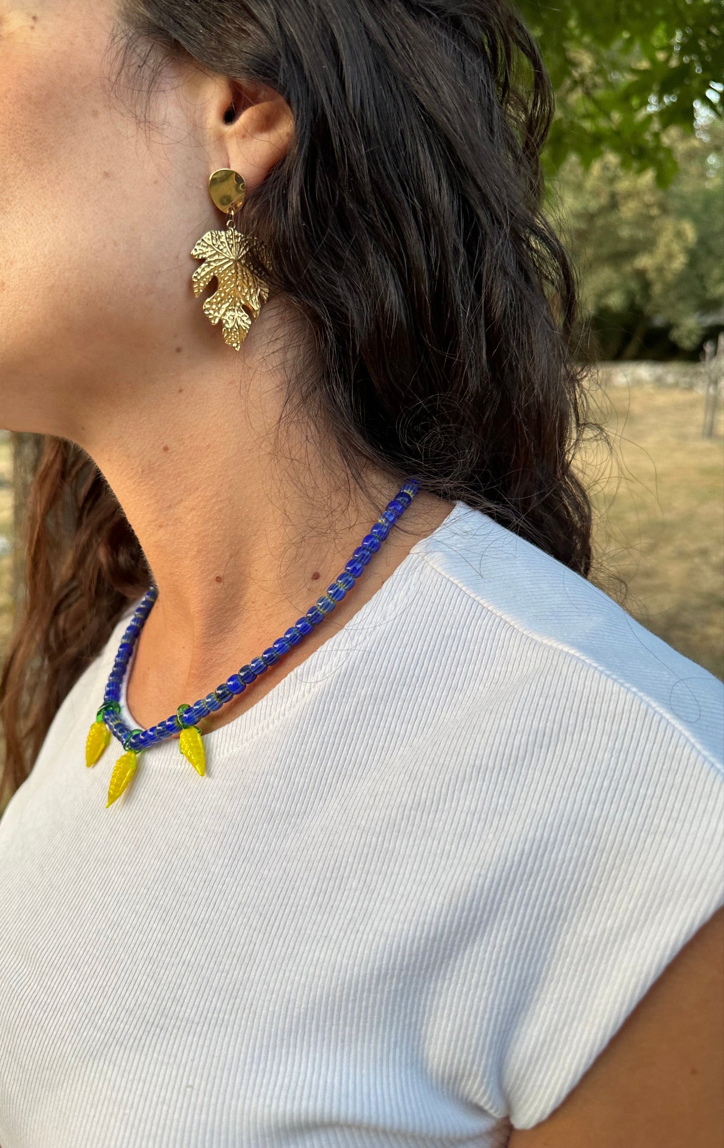 Collar hecho a mano con cuentas de cerámica azul y con tres abalorios con forma de mazorcas de maíz de cristal de murano en color amarillo. Cierre ajustable de acero inoxidable