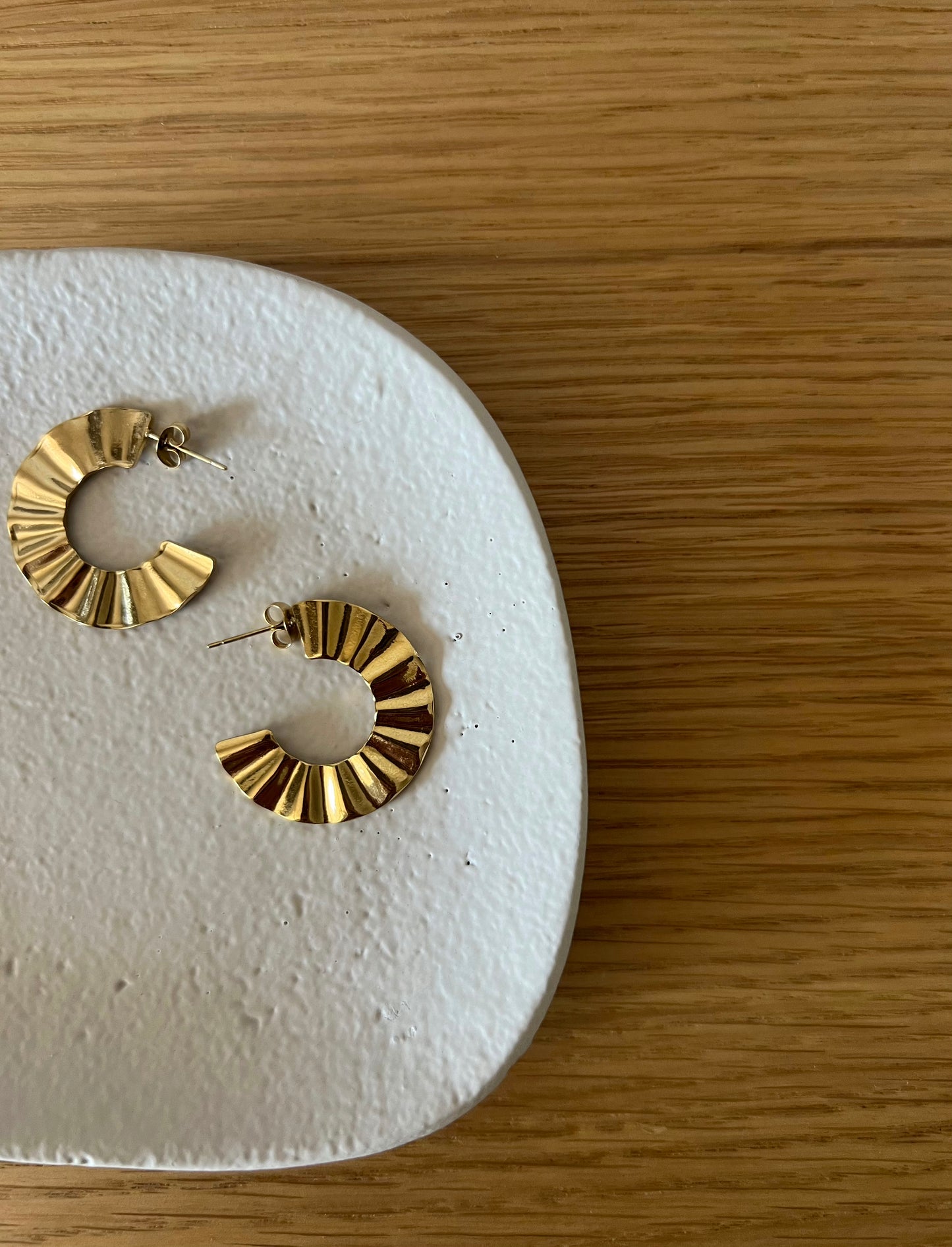 Aros planos con relieve de acero inoxidable en color oro. Estos pendientes son perfectos para elevar tus looks en el día a día. Son hipoalergénicos.