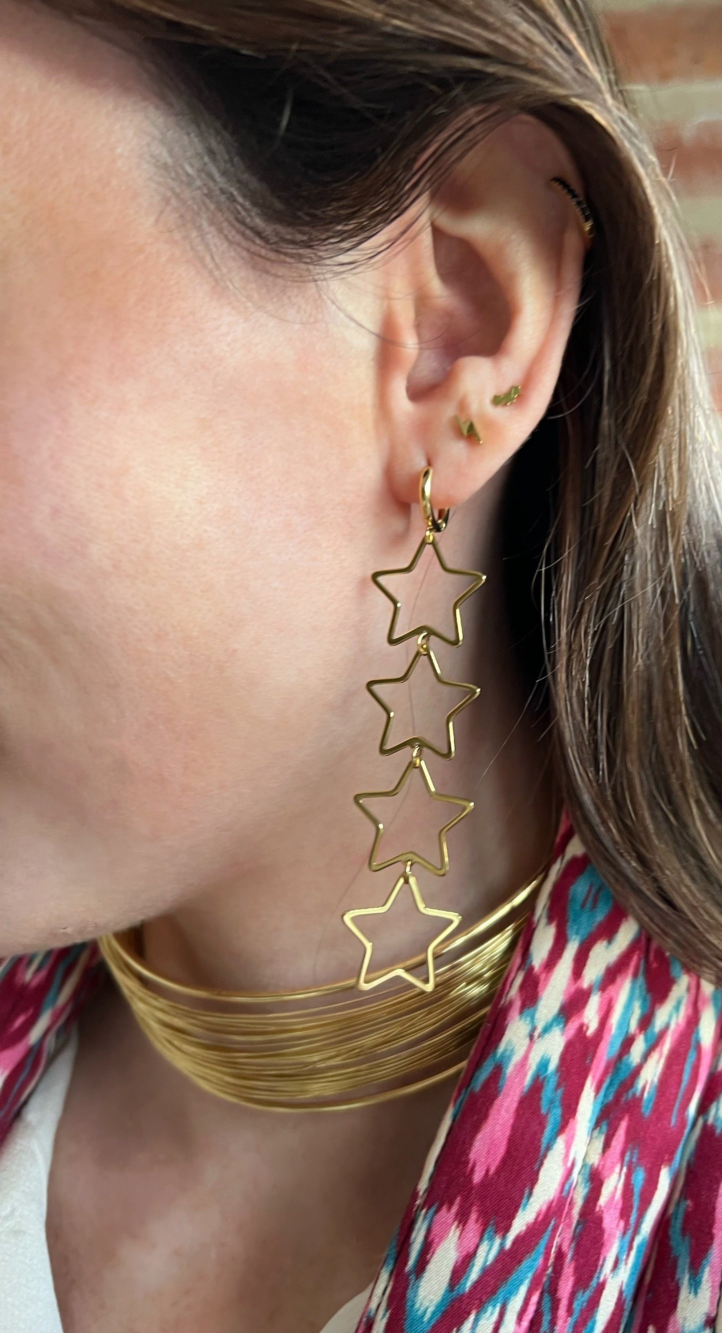 Pendientes aro con cuatro estrellas colgantes de color oro. Son de acero inoxidable e hipoalergénicos.