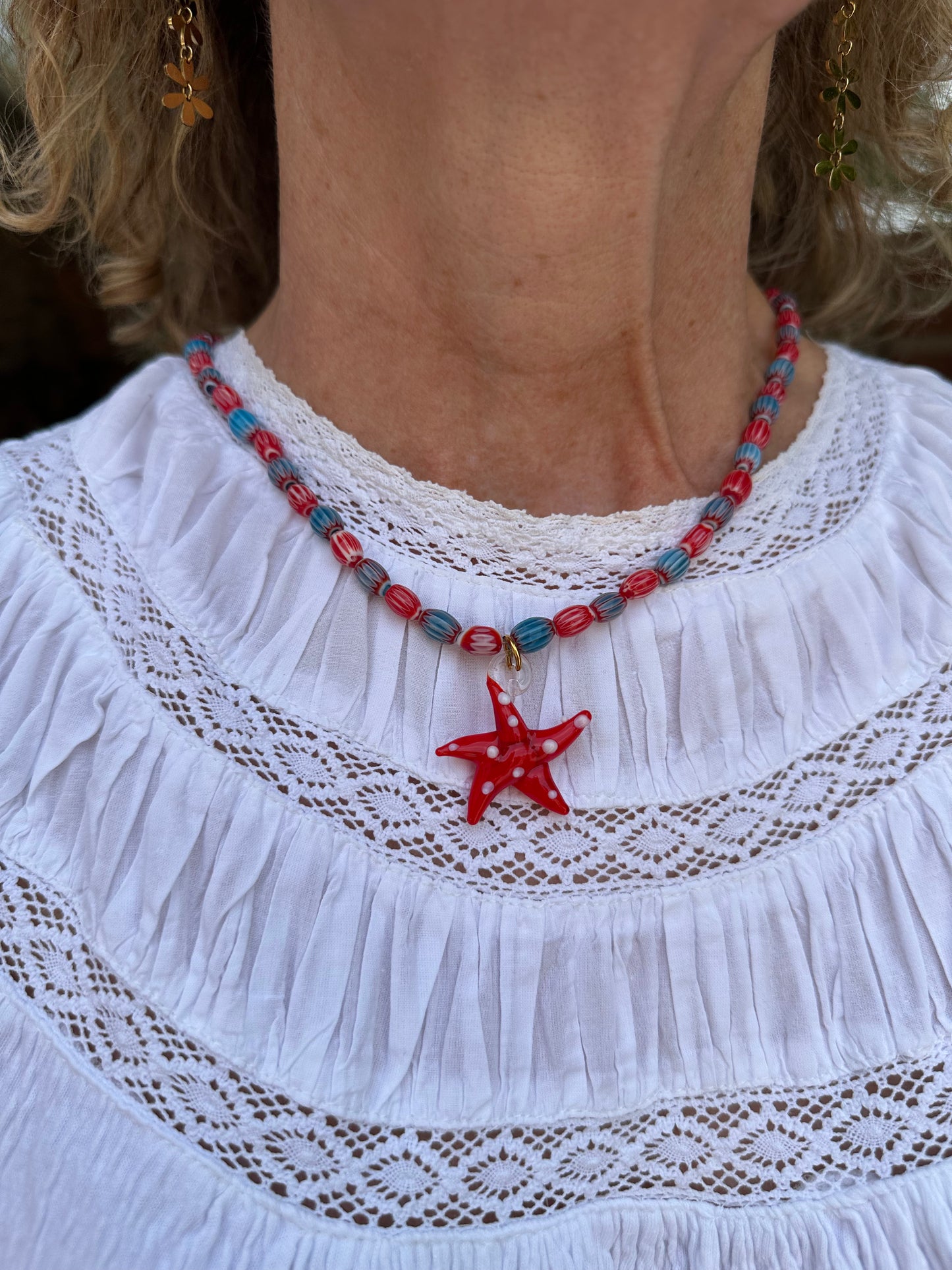 Collar hecho a mano con cuentas de cerámica azul y rojo con un abalorio con forma de estrella de mar de cristal de murano en color rojo. Cierre ajustable de acero inoxidable.