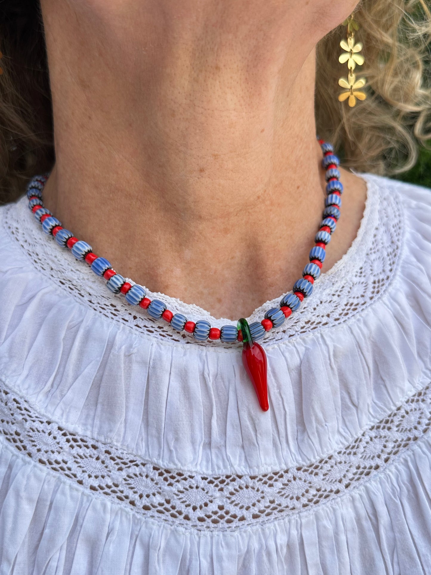 Collar hecho a mano con cuentas de cerámica azul y bolitas rojas, con un abalorio con forma de chili de cristal de murano en color rojo y verde. Cierre ajustable