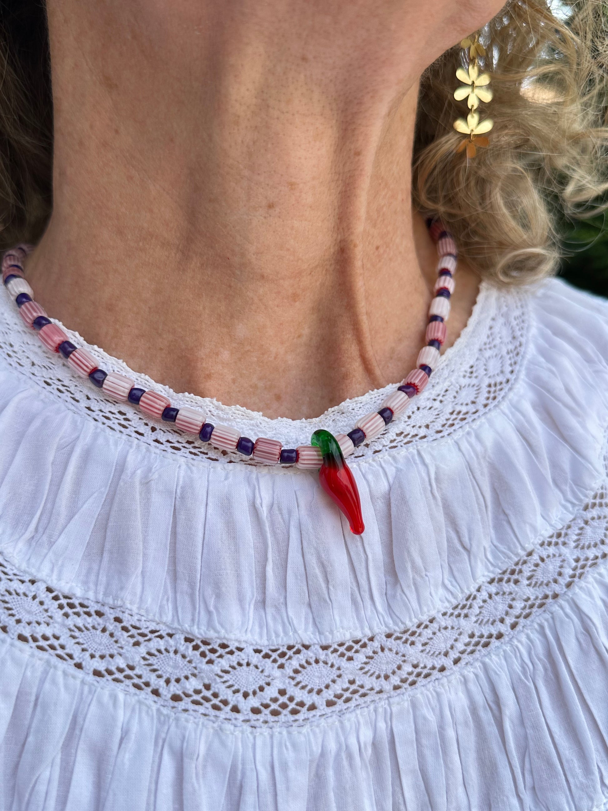 Collar hecho a mano con cuentas de cerámica blancas y cuentas azules, con un abalorio con forma de chili de cristal de murano en color rojo y verde. Cierre ajustable