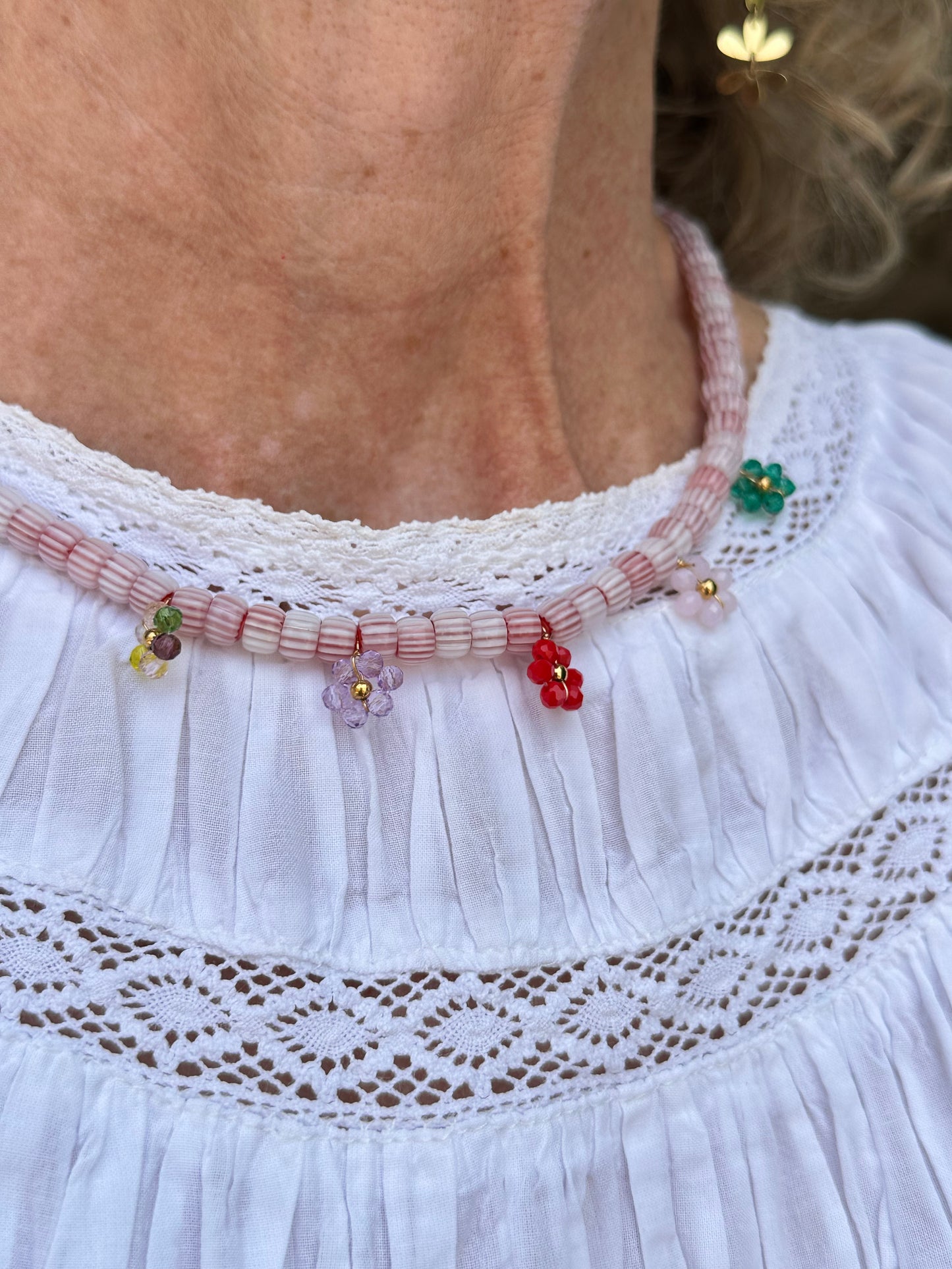Collar hecho a mano con cuentas de cerámica blancas y bolitas formando florecitas. Cierre ajustable de acero inoxidable