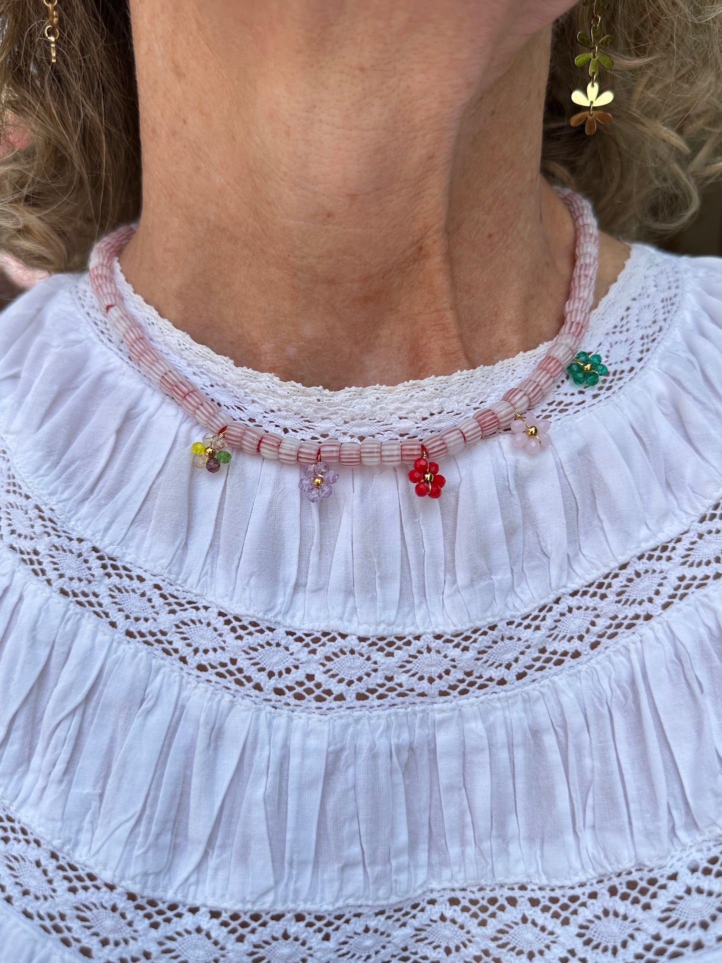 Collar hecho a mano con cuentas de cerámica blancas y bolitas formando florecitas. Cierre ajustable de acero inoxidable