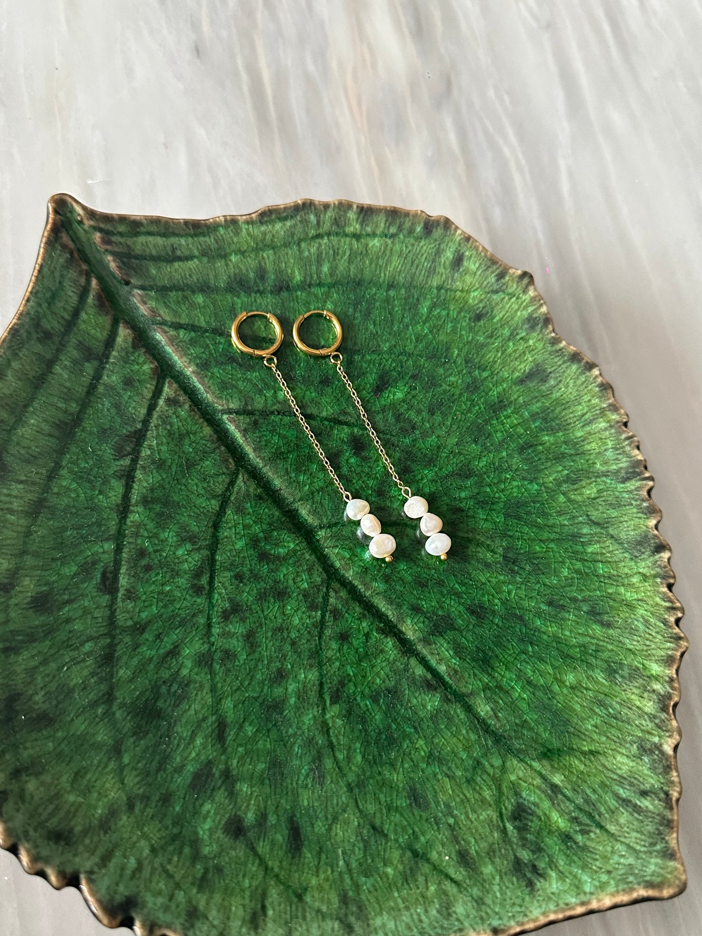 Pendientes de acero inoxidable en color dorado largos con tres perlas. Estos pendientes son perfectos para elevar tus looks.