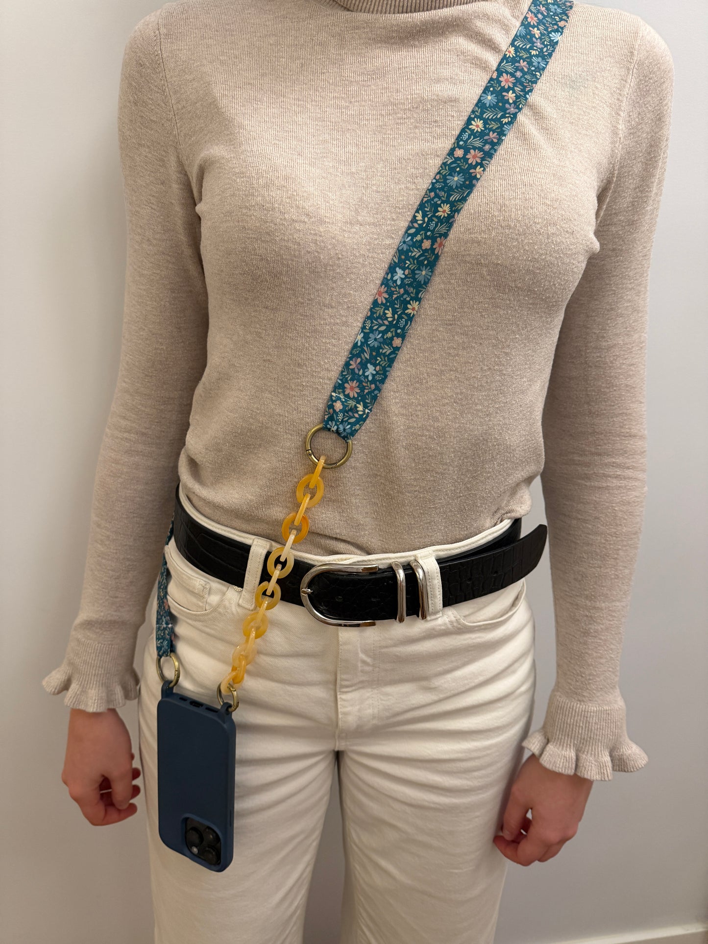 Cuelgamóvil con tela de color azul con flores y con eslabones en color beige. Ajustable y con arandelas de acero inoxidable.