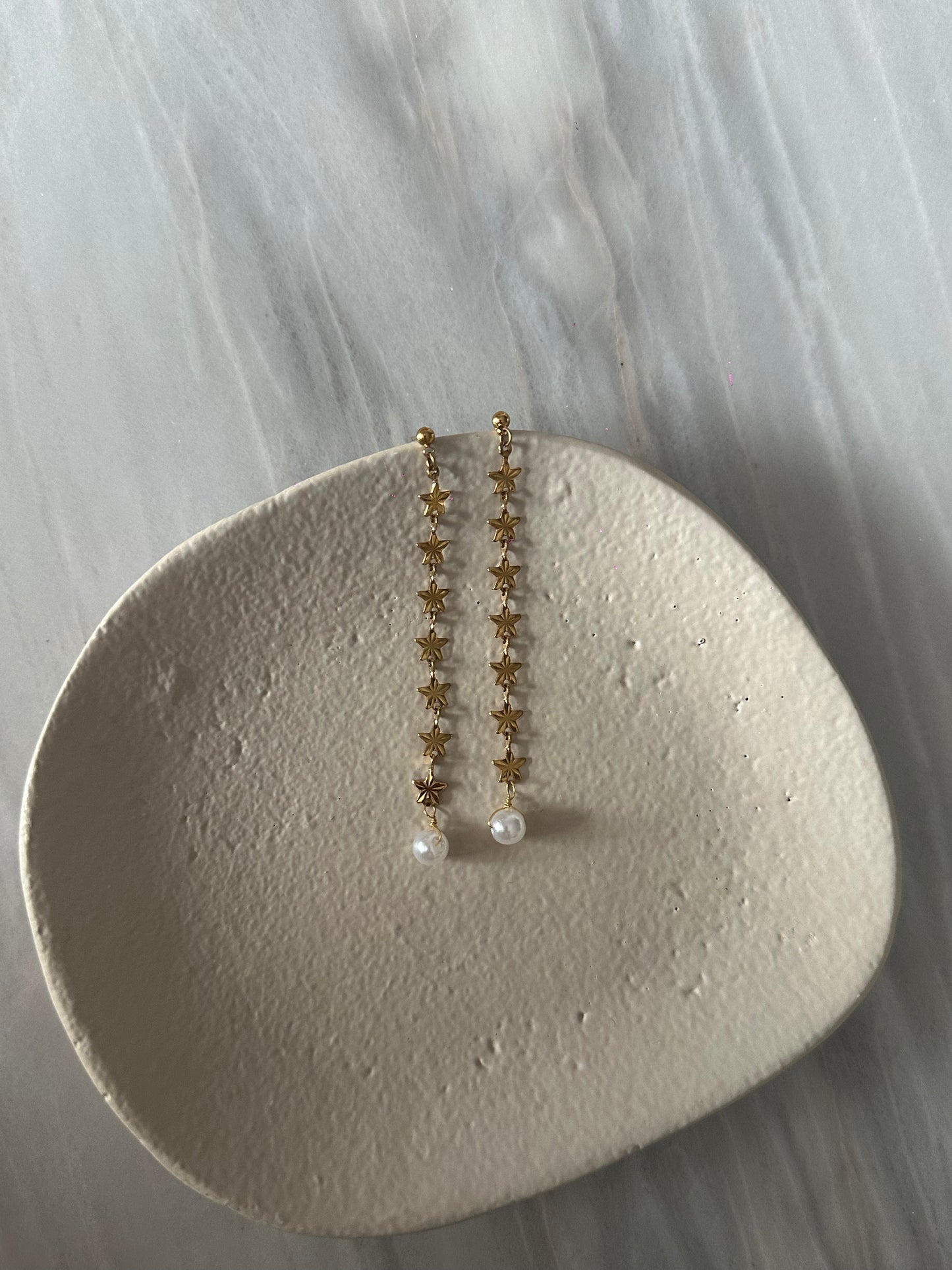 Pendientes de acero inoxidable largos con estrellas doradas y una perla. Estos pendientes son perfectos para elevar tus looks.