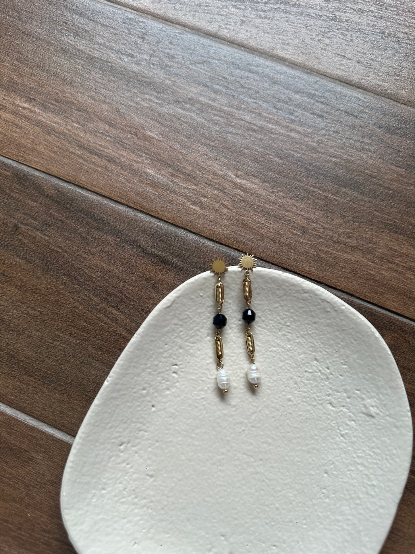 Pendientes largos de acero inoxidable en color dorado con perla de río colgando. Estos pendientes son perfectos para elevar tus looks.