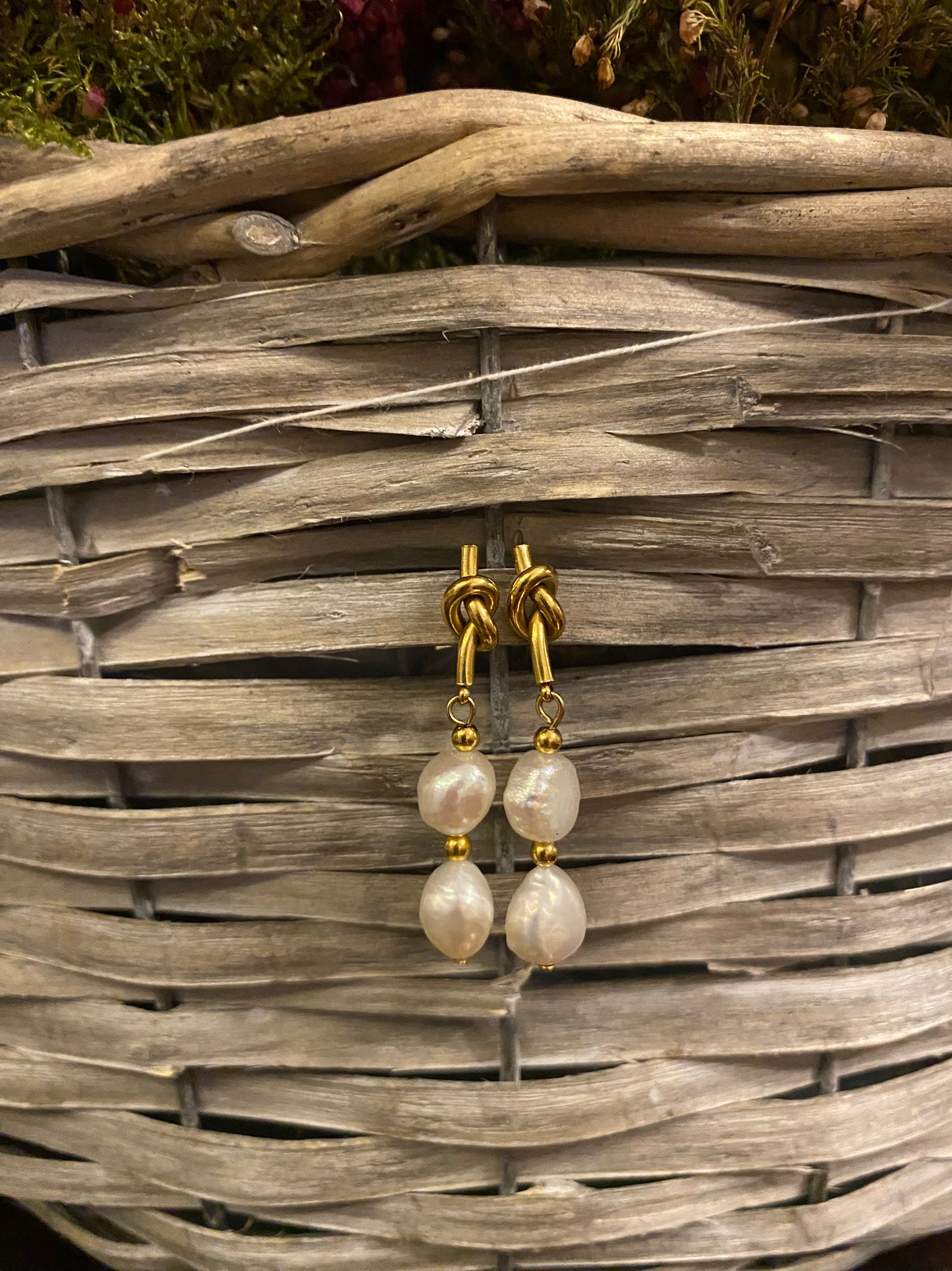 Pendientes de acero inoxidable en color dorado con dos perlas de río. Cierre con forma de nudo. Estos pendientes son perfectos para elevar tus looks.