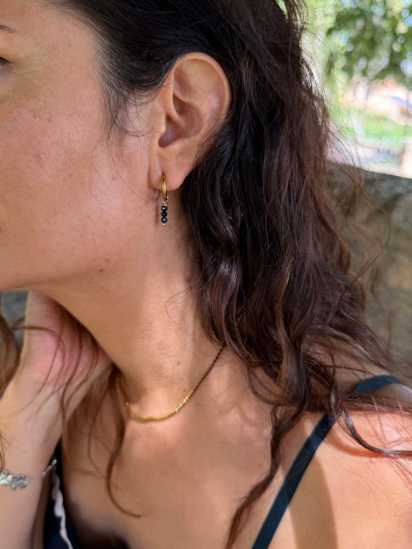 Pendientes de aro de acero inoxidable en color dorado con tres bolitas negras colgando. Estos pendientes son perfectos para elevar tus looks.
