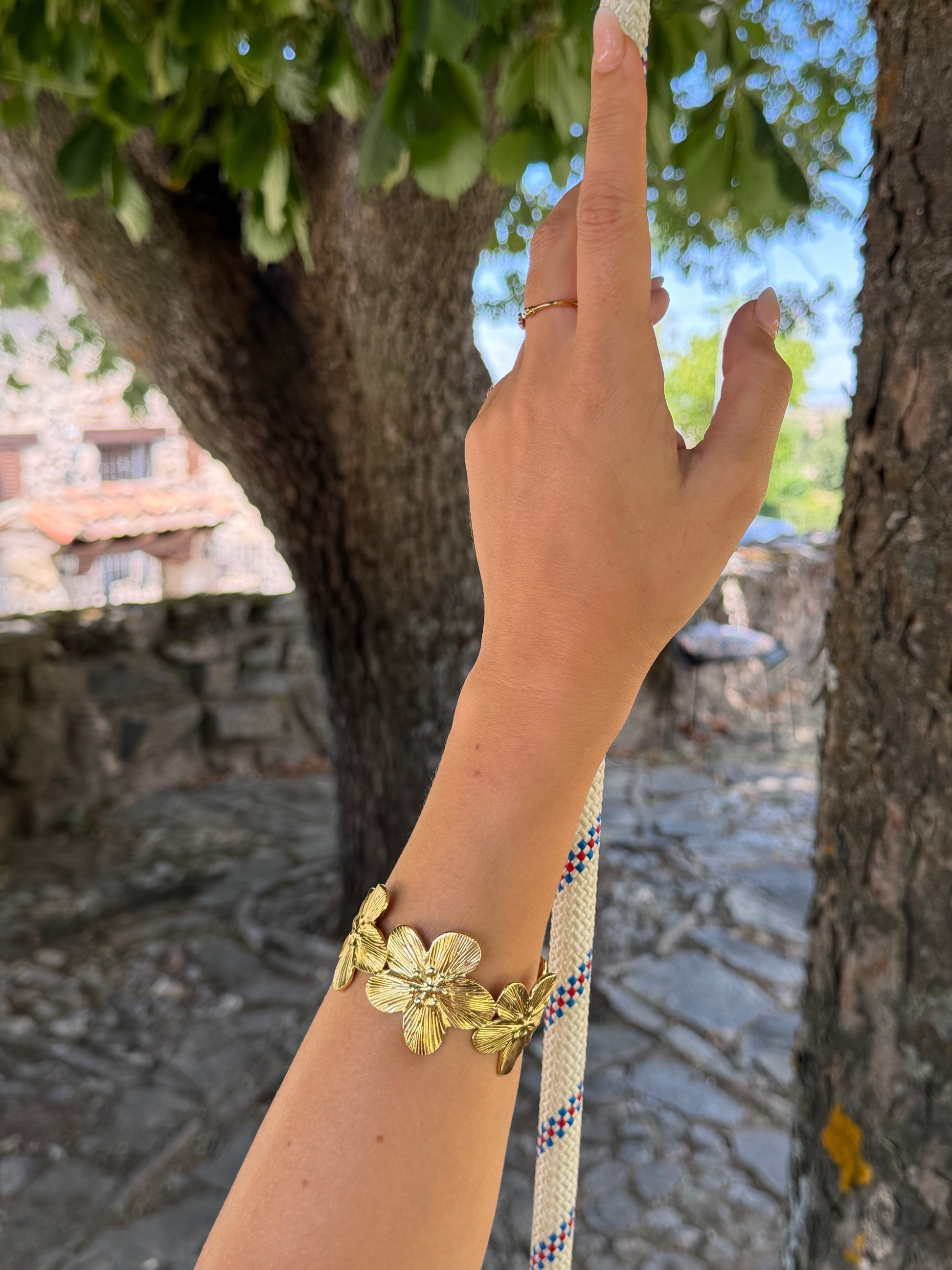 Brazalete de acero inoxidable ajustable. En color dorado. Diseño muy original con flores.