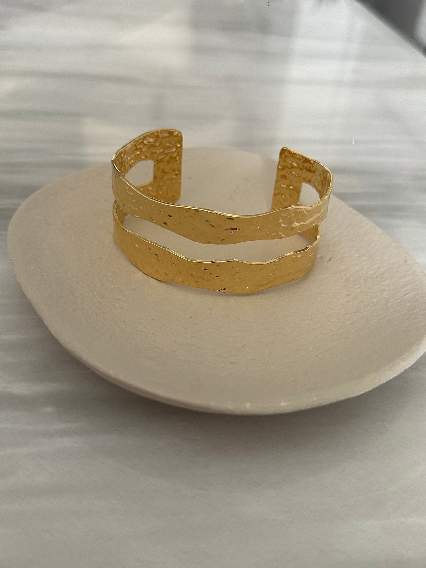 Brazalete de acero inoxidable ajustable. En color dorado. Diseño muy original.