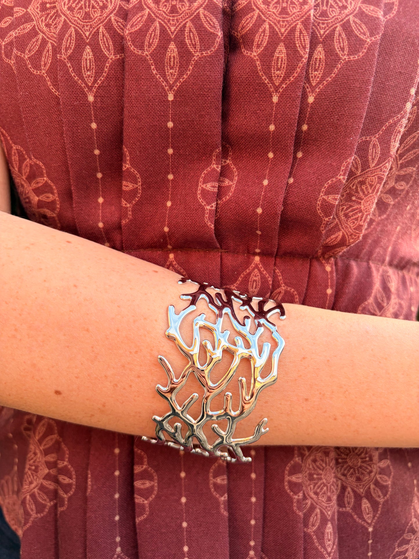 Brazalete de acero inoxidable ajustable. En color plateado.