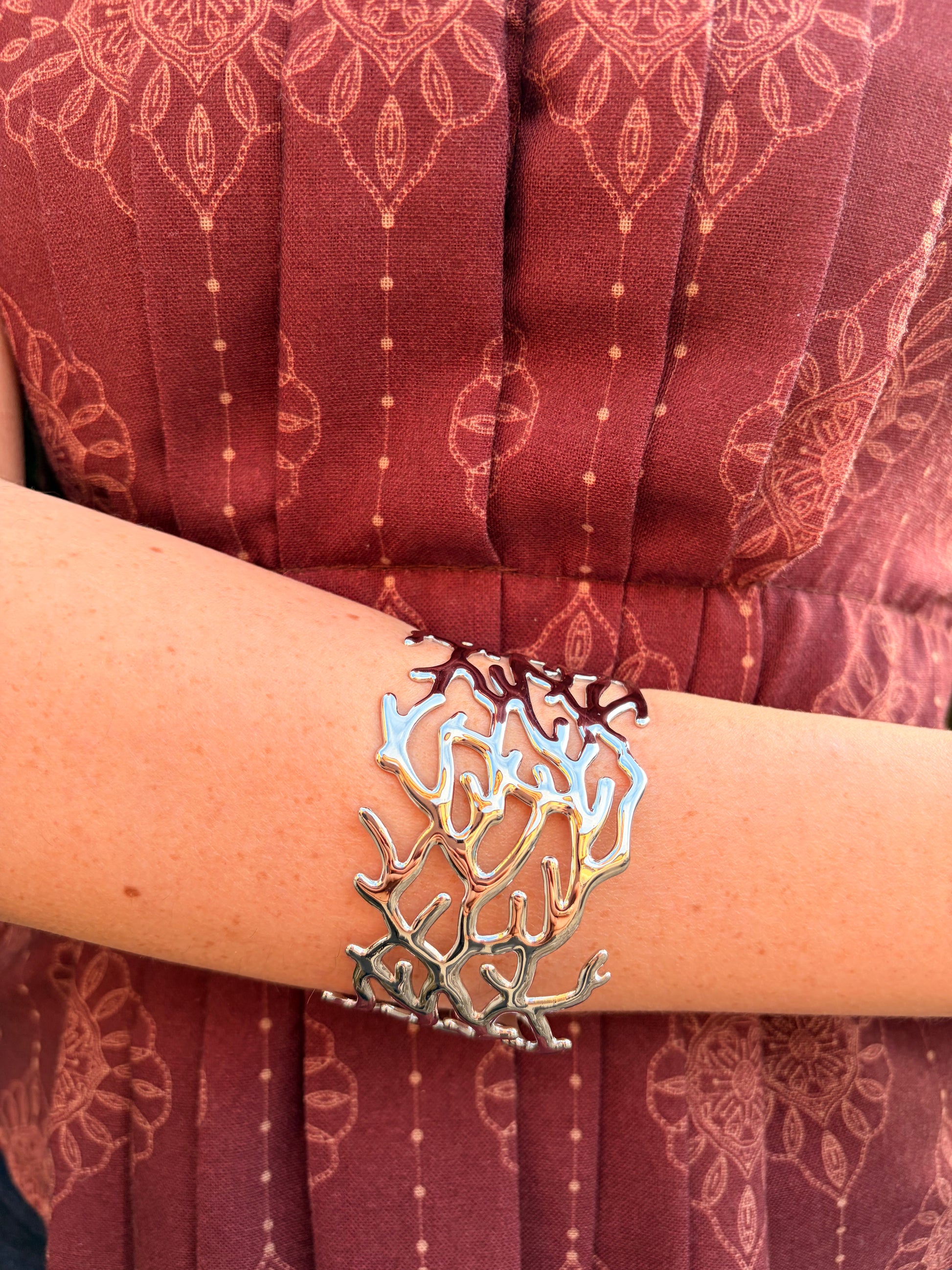 Brazalete de acero inoxidable ajustable. En color plateado.