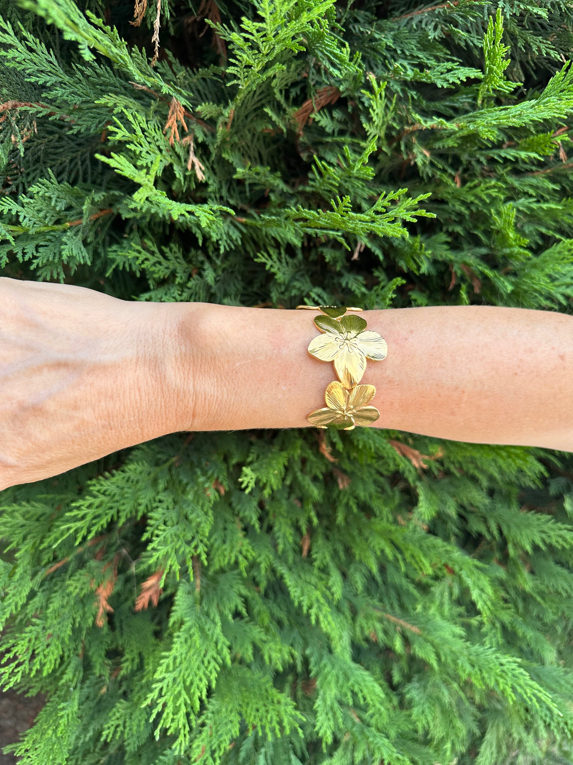 Brazalete de acero inoxidable ajustable. En color dorado. Diseño muy original con flores.