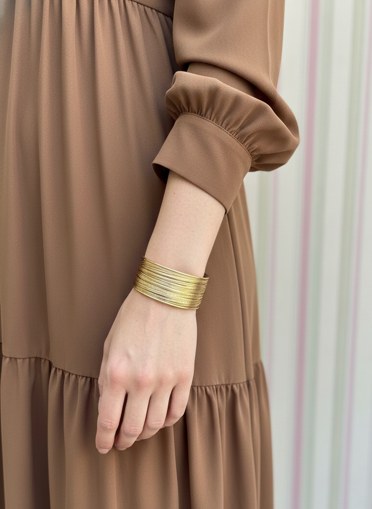 Brazalete de acero inoxidable ajustable. En color dorado.