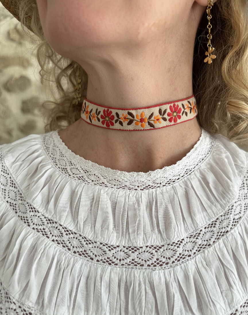 Modelo con choker de tela con flores bordadas, cierre ajustable y de acero inoxidable.