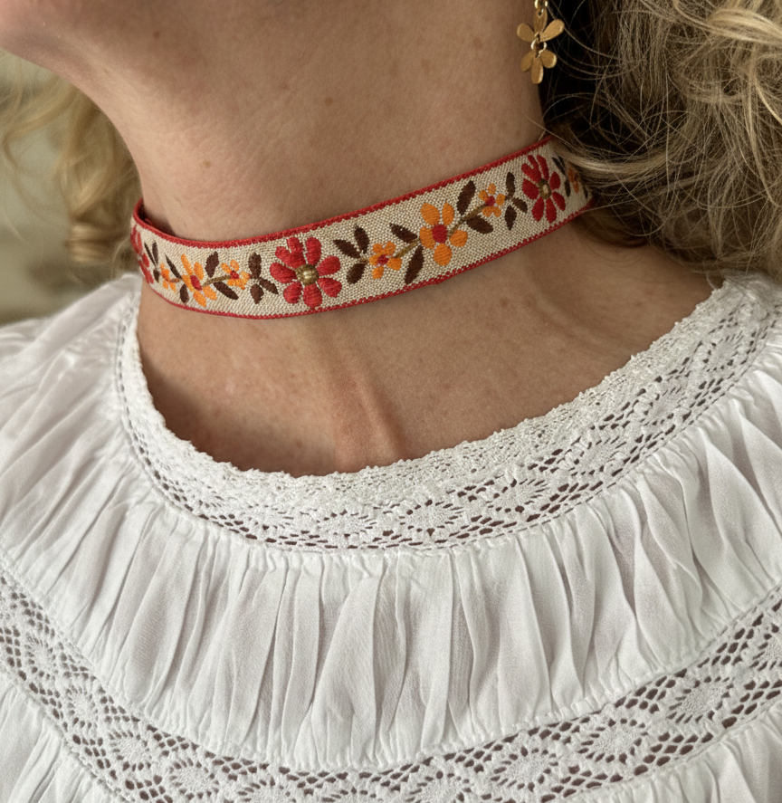 Modelo con choker de tela con flores bordadas, cierre ajustable y de acero inoxidable.