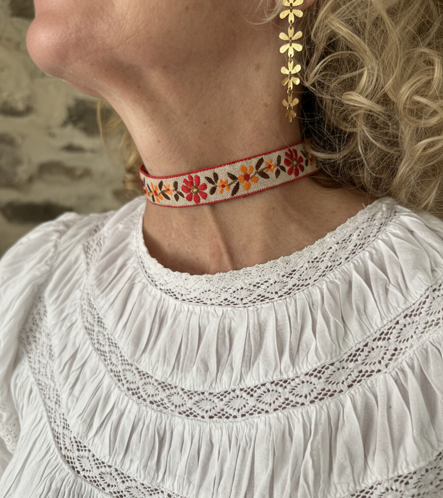 Modelo con choker de tela con flores bordadas, cierre ajustable y de acero inoxidable.