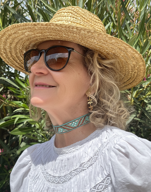 Modelo con choker de tela con patrón étnico en tonos turquesa y marrón con detalles dorados, cierre de acero inoxidable.