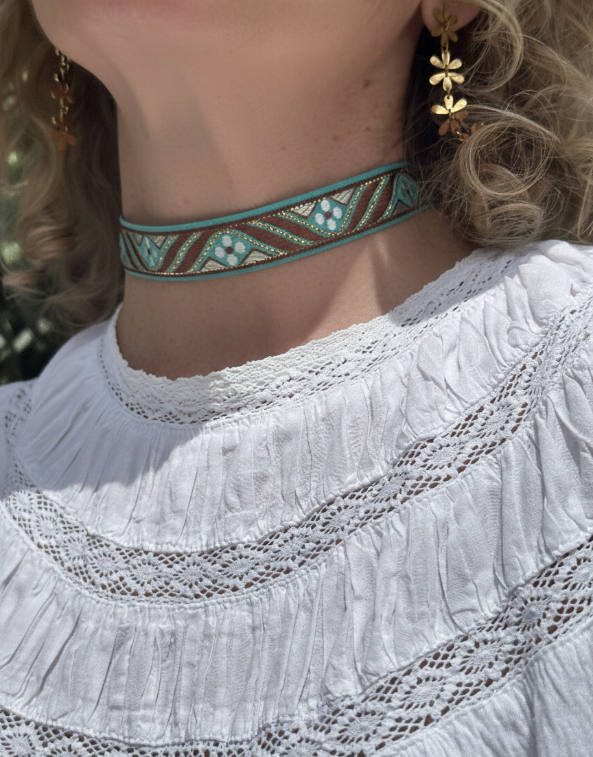 Choker de tela con patrón étnico en tonos turquesa y marrón con detalles dorados, cierre de acero inoxidable.