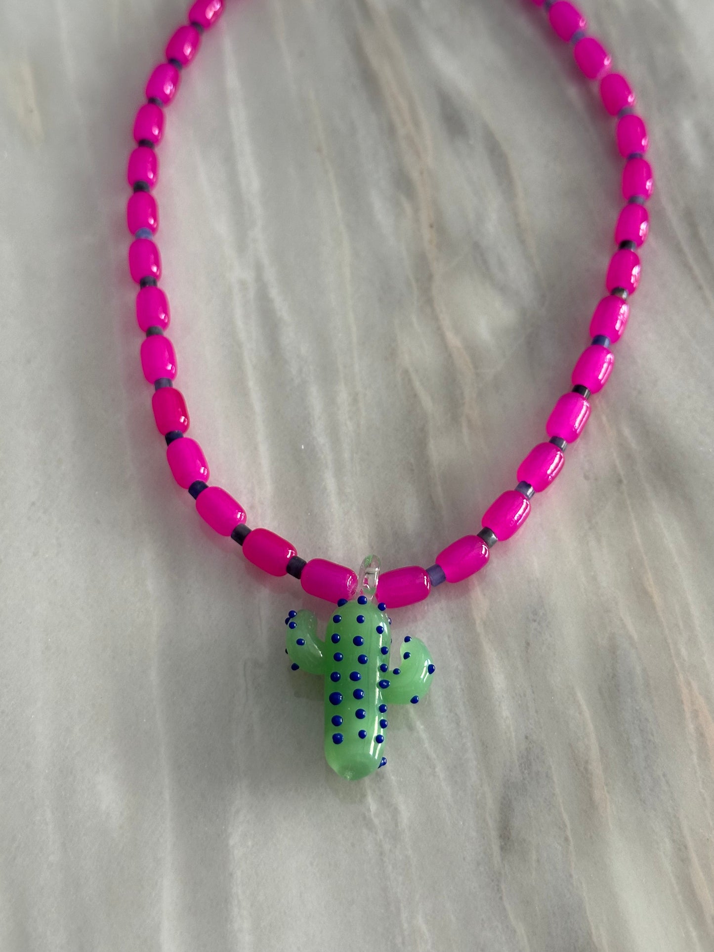 Collar hecho a mano con cuentas de cerámica rosa y piedra sodalita (Azul), con un abalorio con forma de cactus de cristal de murano en tono verde con puntos azules