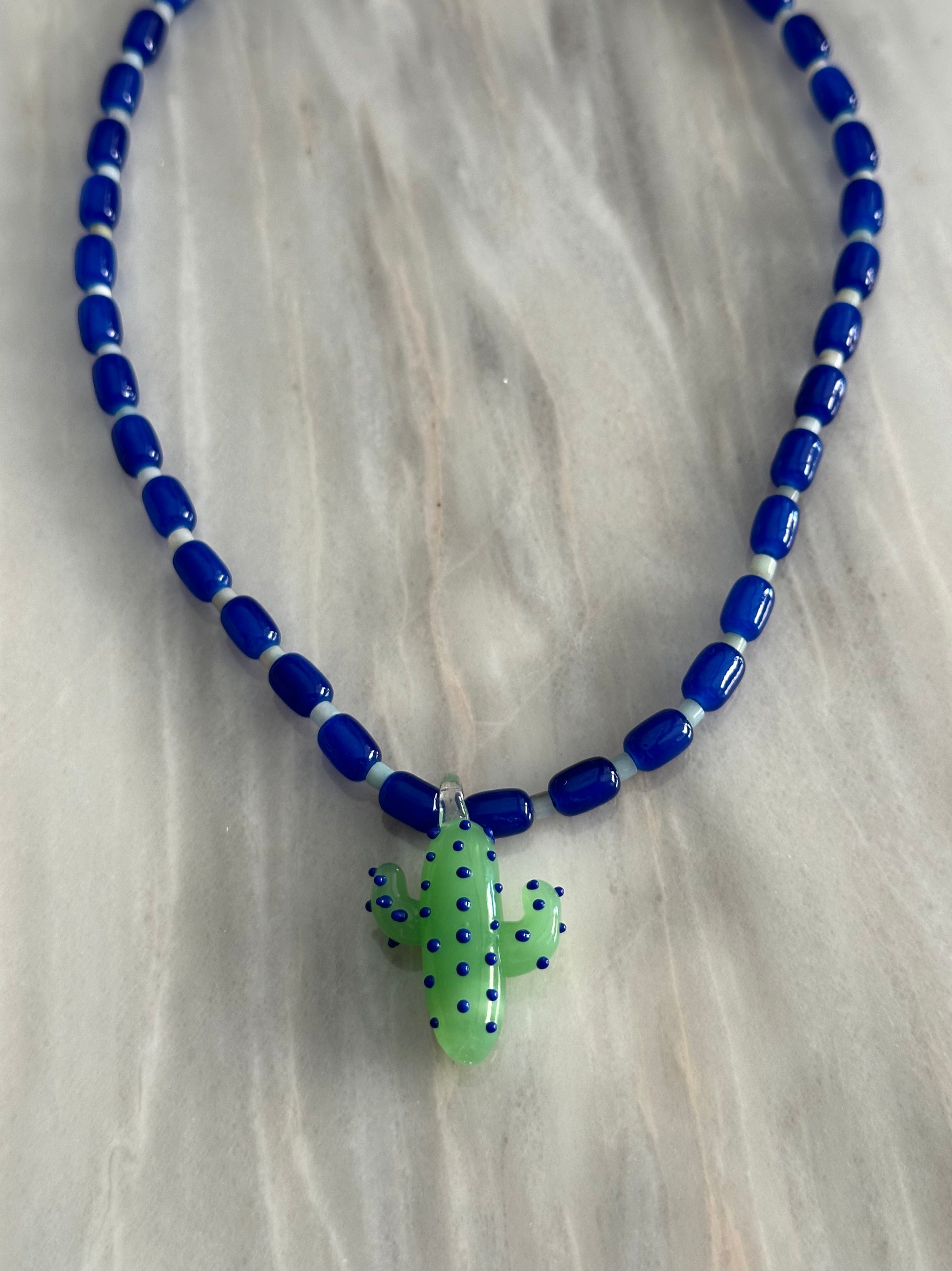 Collar hecho a mano con cuentas de cerámica azul y piedra agata de arbol con un abalorio con forma de cactus de cristal de murano en tono verde con puntos azules