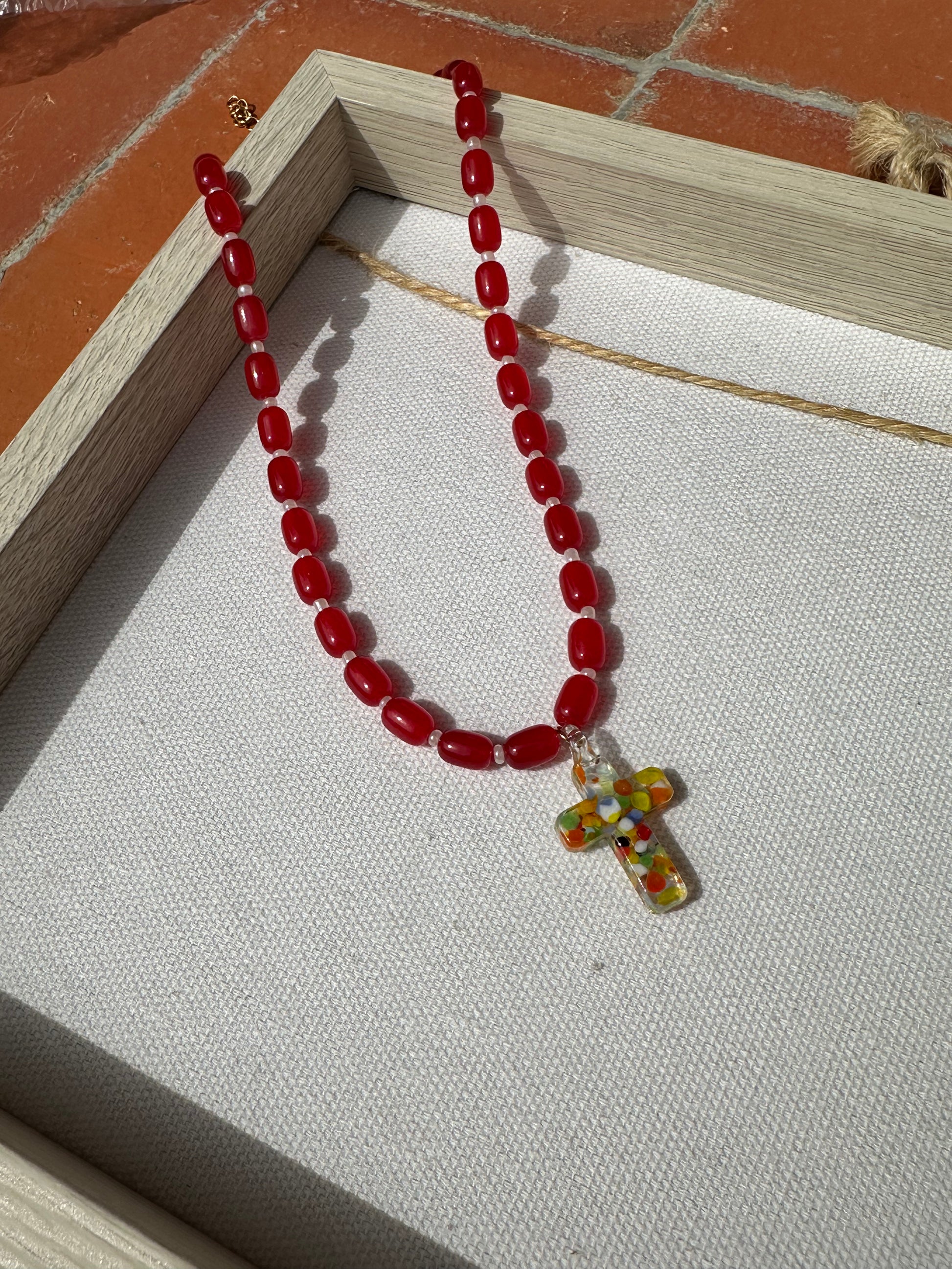 Collar hecho a mano con cuentas de cerámica roja y con un abalorio con forma de cruz de cristal de murano en varios tonos