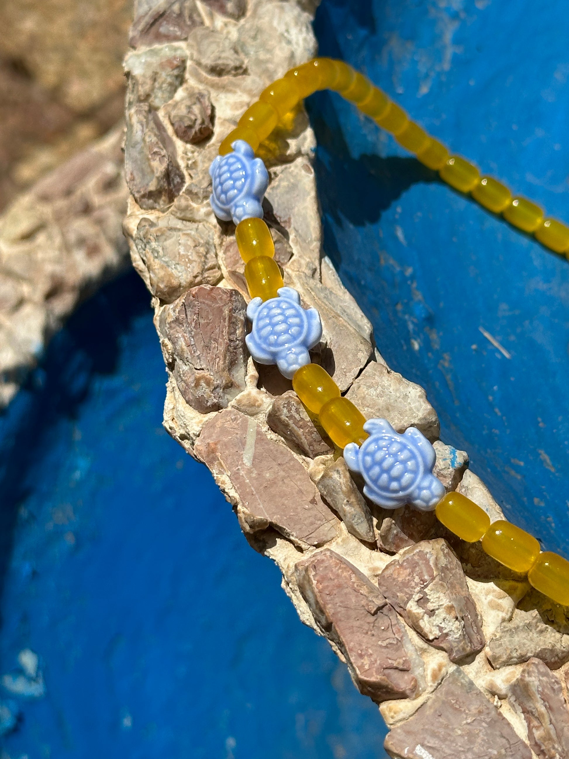 Collar hecho a mano con bolas de cerámica amarilla y con tortugas de cerámica en azul. Con cierre ajustable de acero inoxidable