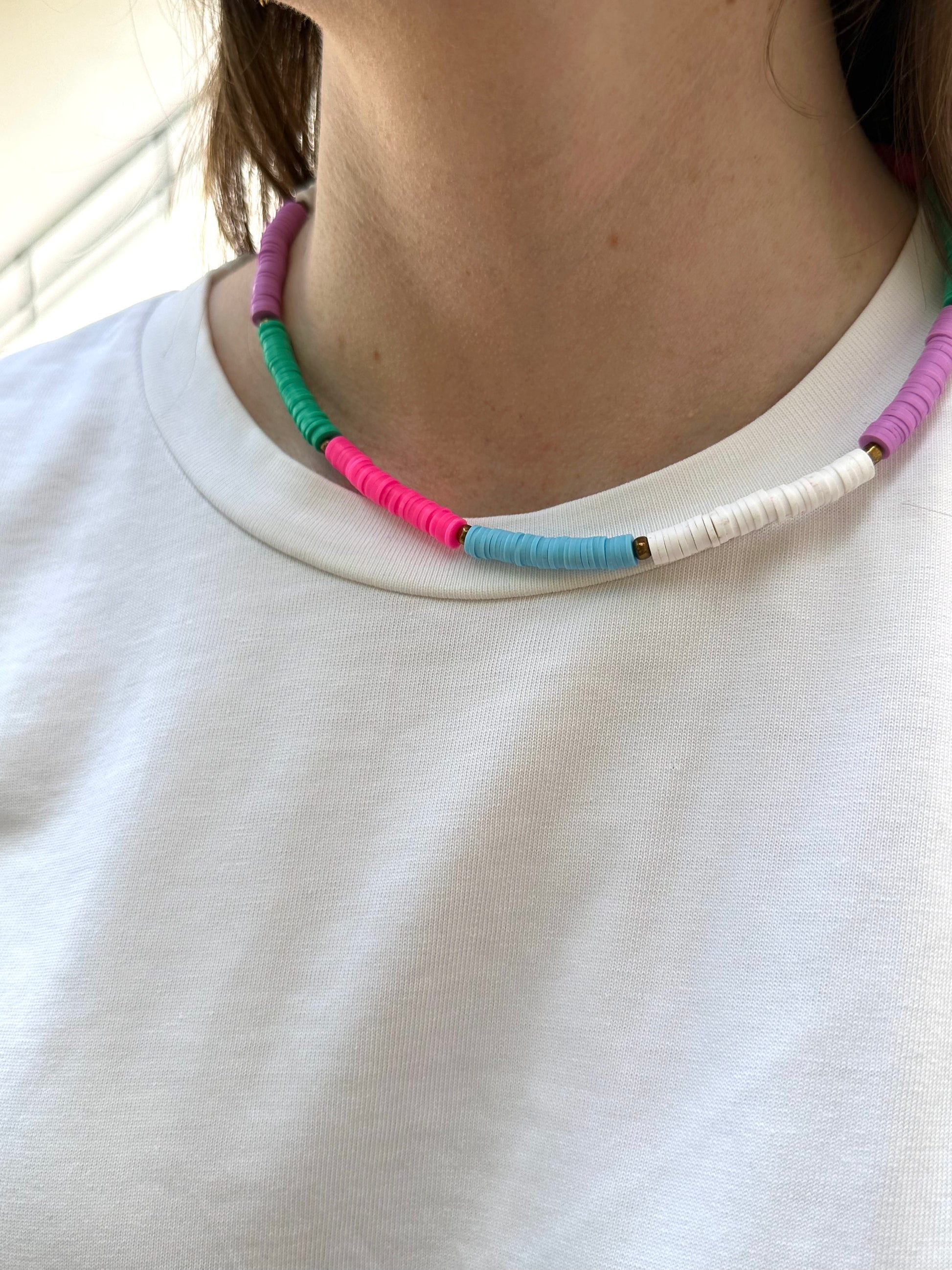 Collar hecho a mano con arcilla polimérica en varios colores fosforitos: rosa, azul, verde, lila y blanco, separados por cuentas espaciadoras doradas. Con cierre ajustable en acero inoxidable 