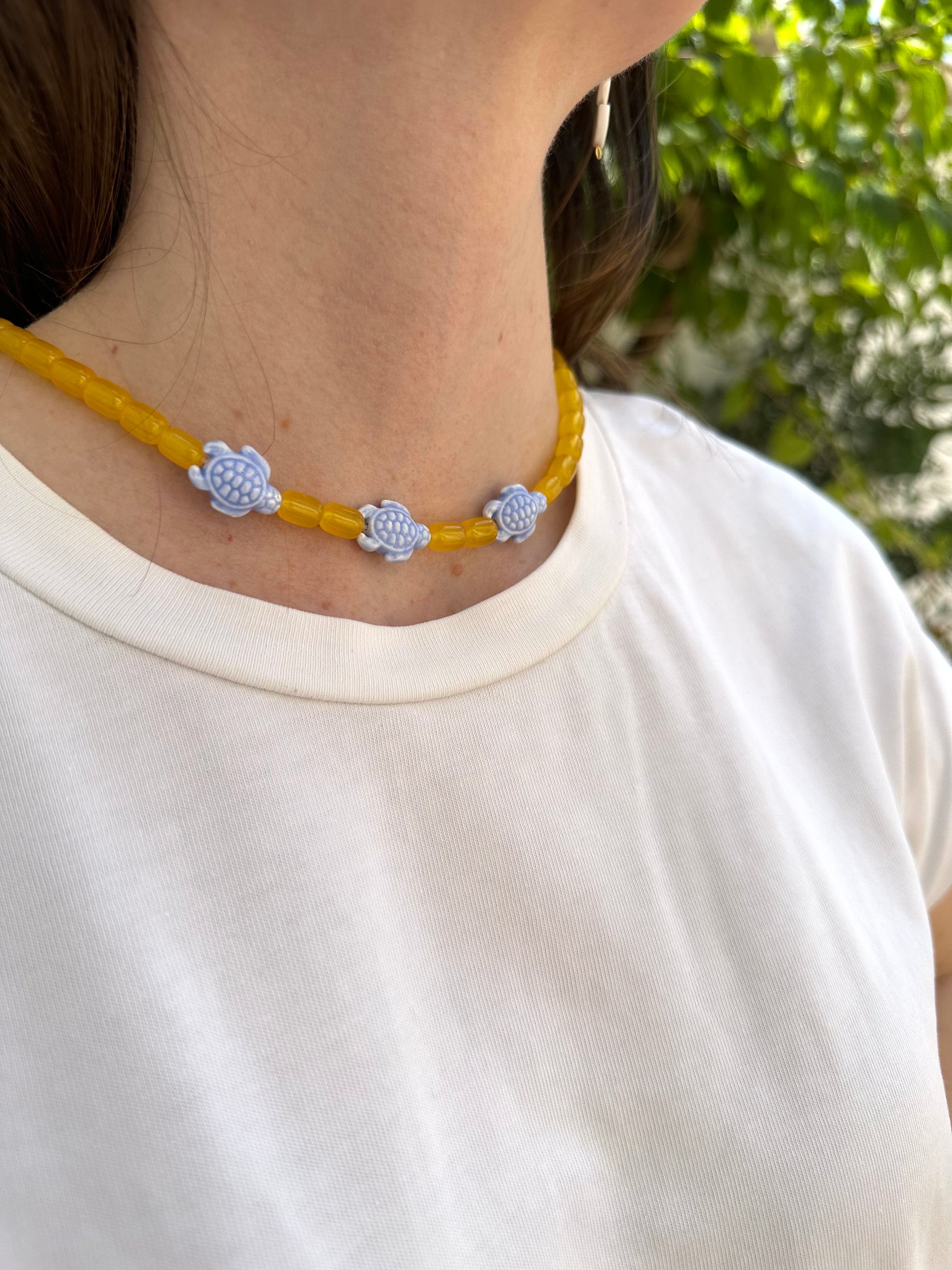 Collar hecho a mano con bolas de cerámica amarilla y con tortugas de cerámica en azul. Con cierre ajustable de acero inoxidable