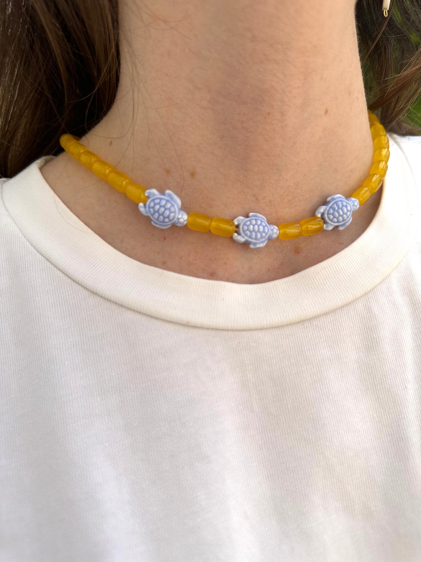 Collar hecho a mano con bolas de cerámica amarilla y con tortugas de cerámica en azul. Con cierre ajustable de acero inoxidable