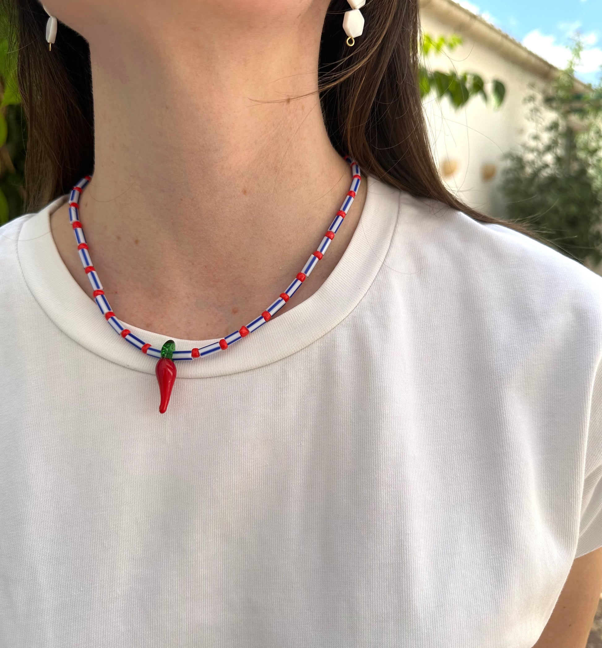 Collar hecho a mano con cuentas rayadas en azul, bolitas rojas y con un abalorio de cristal de murano con forma de chili. Con cierre ajustable de acero inoxidable