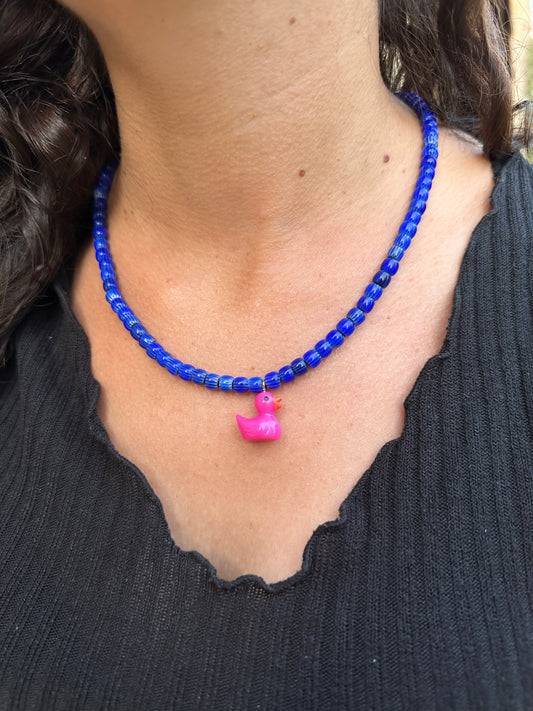 Collar hecho a mano con cuentas de cerámica azul y con un abalorio con forma de patito en color rosa. Cierre ajustable de acero inoxidable